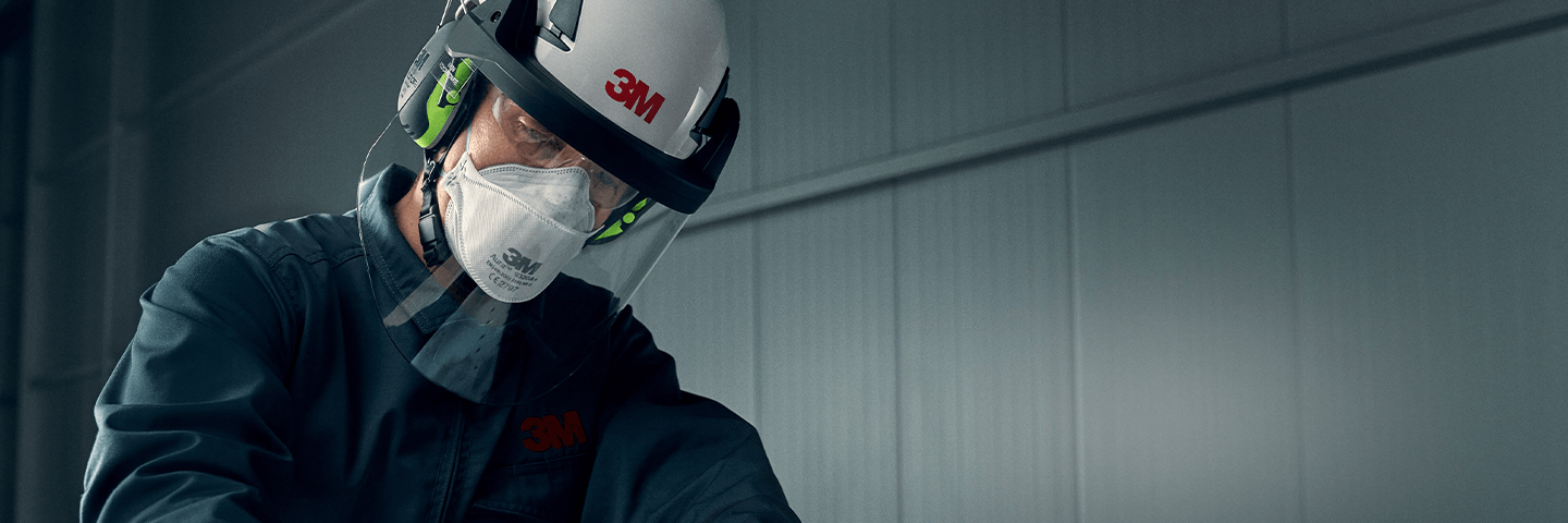 Mann mit Gehörschutz, Helm und Atemschutz beim Arbeiten